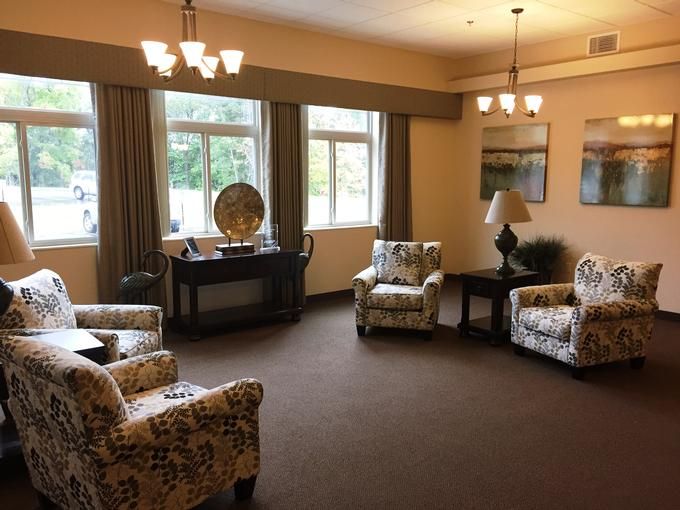 A cozy living room with patterned chairs, a central table, and large windows.