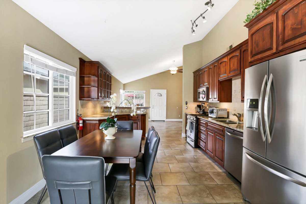 A modern kitchen and dining area with wood cabinets and stainless steel appliances.