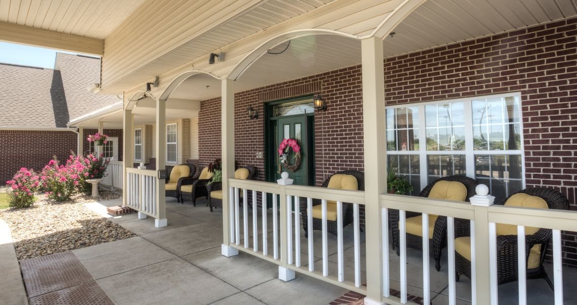 A cozy covered porch with chairs and a decorative wreath on the door.