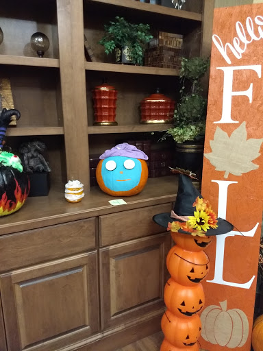 A colorful pumpkin with a playful design, surrounded by various fall decorations.