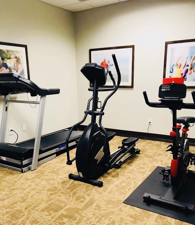 A small gym with a treadmill, elliptical machine, and exercise bike.