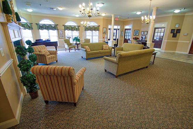 A spacious living room with multiple sofas and armchairs, featuring elegant lighting and decor.