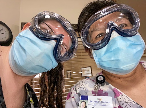 Two healthcare workers taking a selfie while wearing protective gear.