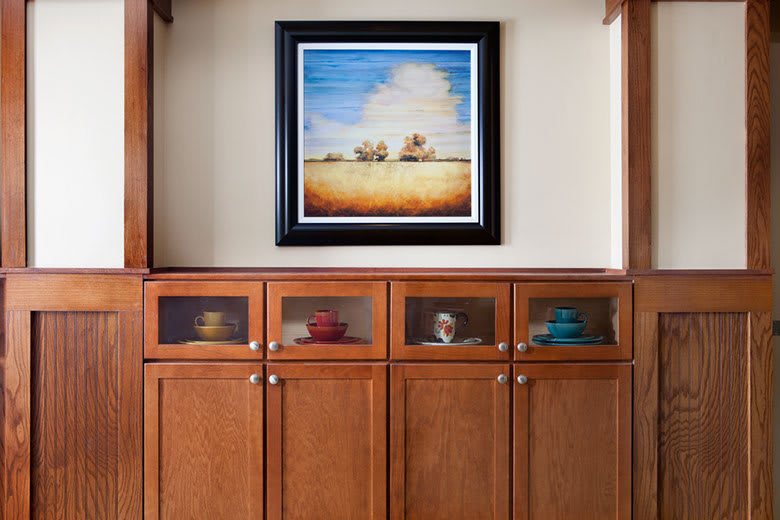 A framed painting hangs above a series of wooden cabinets, showcasing a thoughtful interior design.