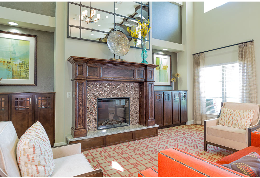 A modern living room featuring a large fireplace with intricate woodwork, high ceilings, and stylish decor.