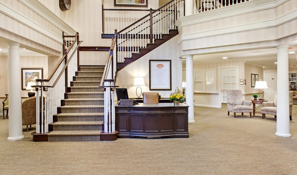 A spacious hotel lobby with a reception desk and staircase.