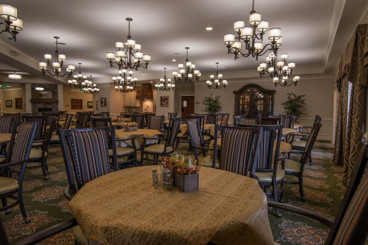 An elegant dining room with multiple tables, chairs, and chandeliers.