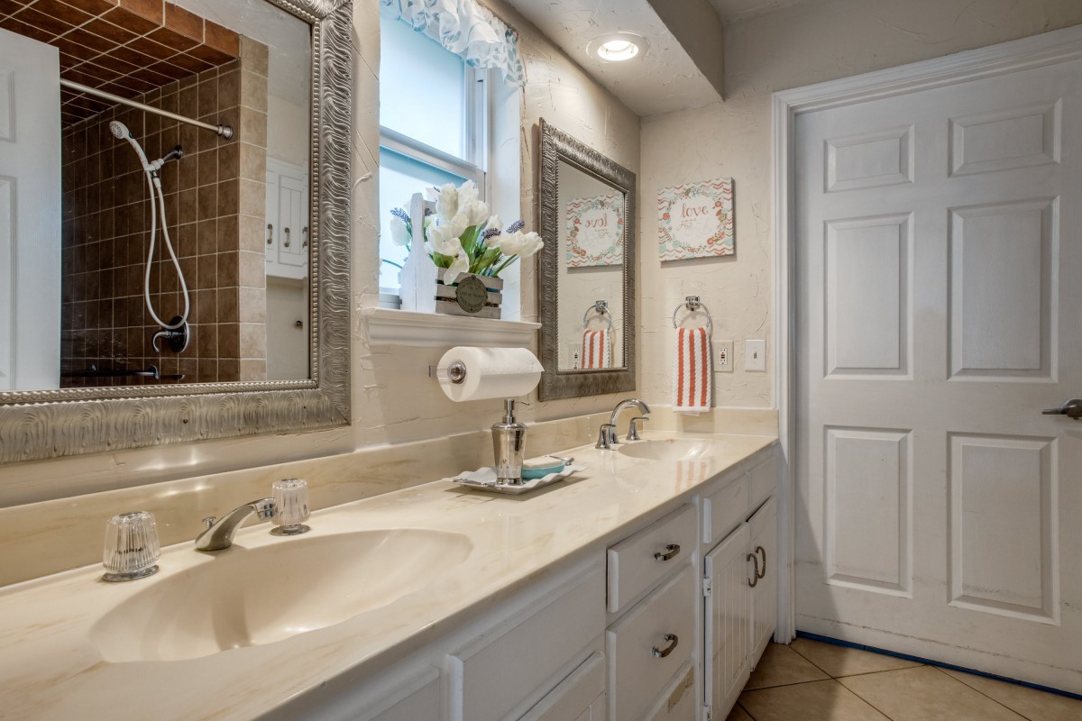 A modern bathroom featuring a double sink with a large mirror and decorative elements.