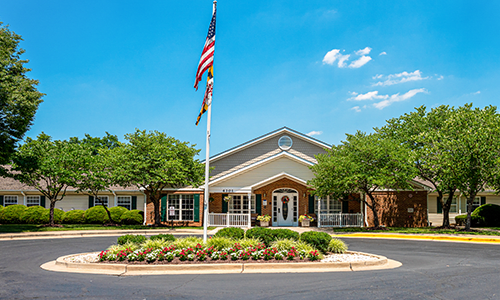 A building with a flagpole and landscaped entrance on a sunny day.
