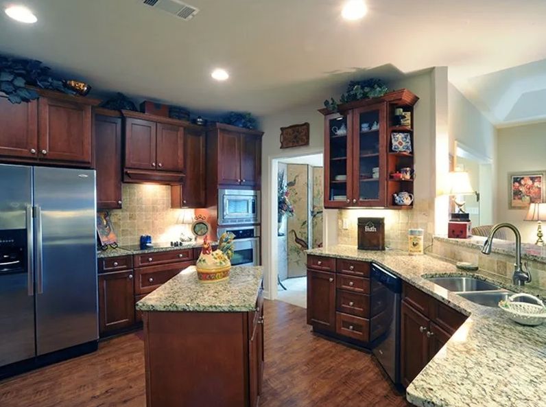 A modern kitchen featuring wooden cabinets and granite countertops, complete with stainless steel appliances and an island.