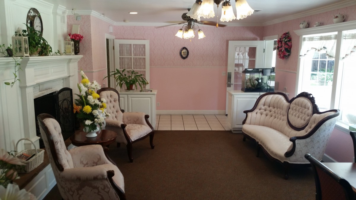A cozy living room with vintage furniture, featuring pink walls and a chandelier.