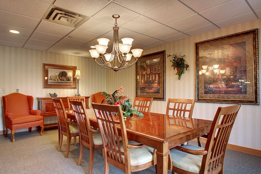 A well-furnished dining room with a large wooden table, surrounding chairs, and a chandelier.