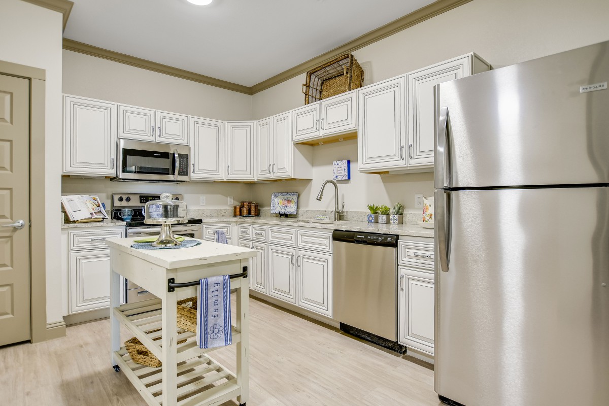 A modern kitchen featuring stainless steel appliances and white cabinets, complete with a central island.