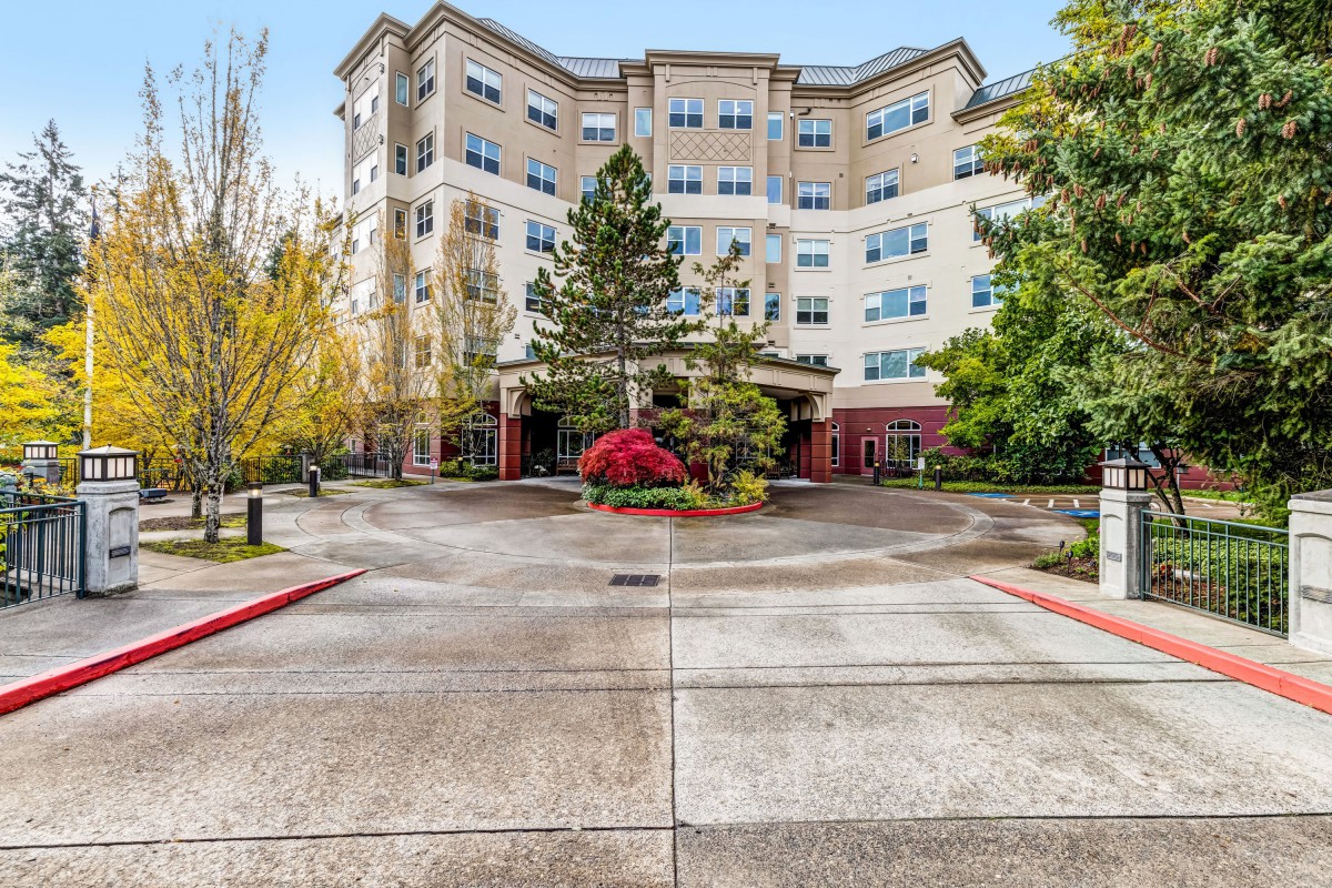 A residential building with a landscaped entrance and driveway.