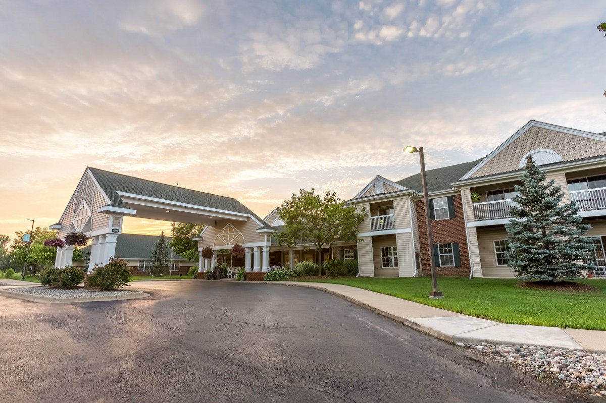 A view of a residential apartment complex at sunset with a driveway leading up to the buildings.
