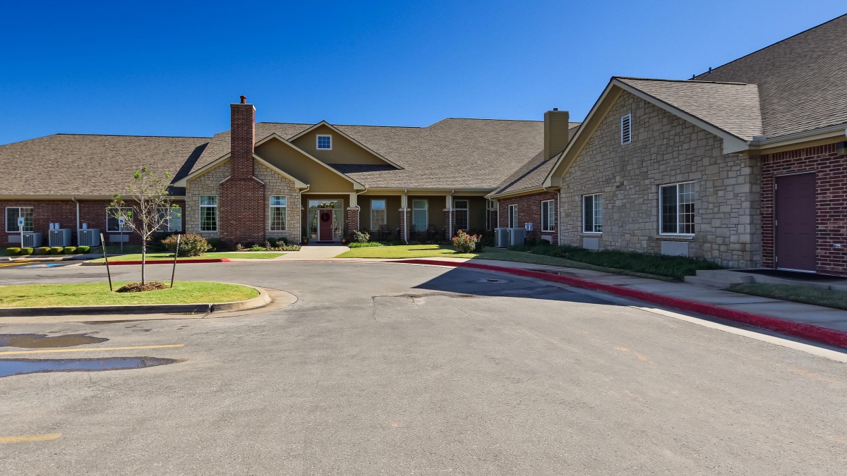 A suburban residential building with a circular driveway under a clear blue sky.