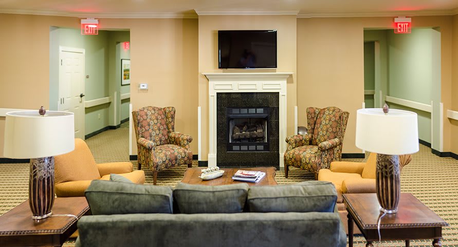 A cozy living room with a fireplace, armchairs, and a sofa facing a mounted television.