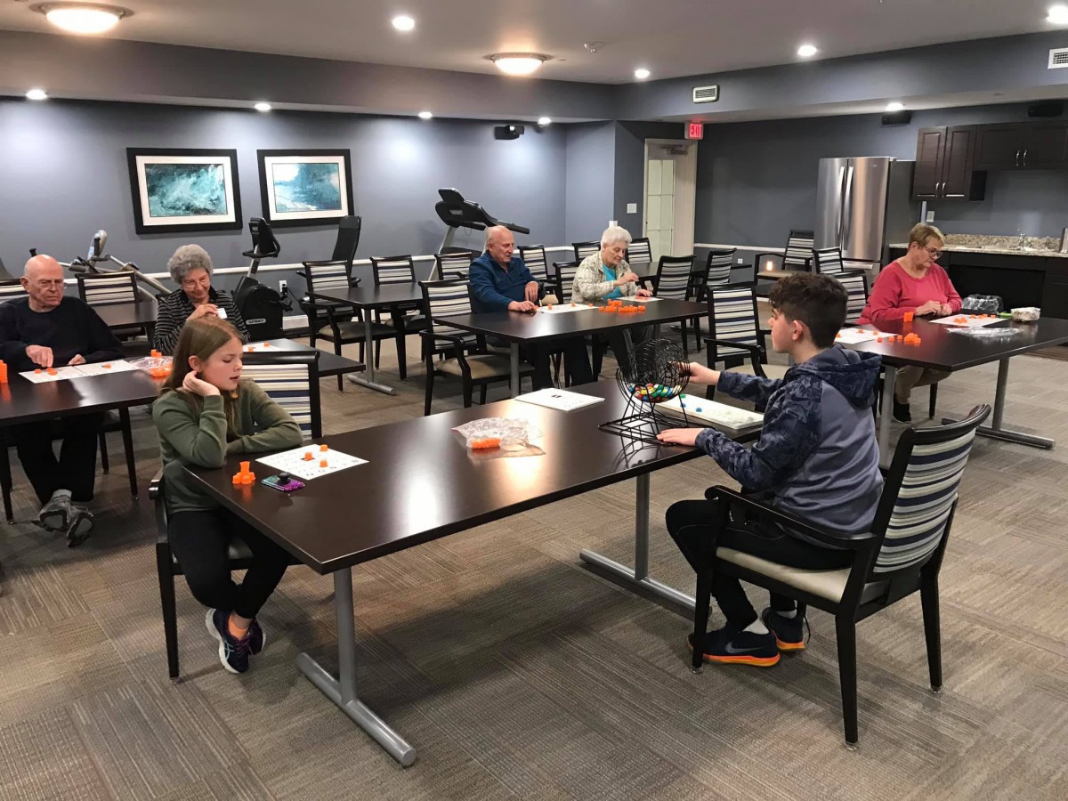 A group of people seated in a conference room setting, participating in a meeting.
