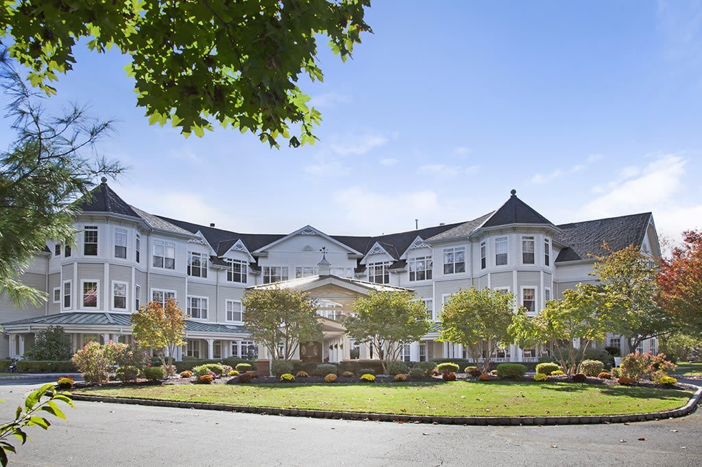 A large, elegant hotel building with a landscaped entrance and bright blue sky.