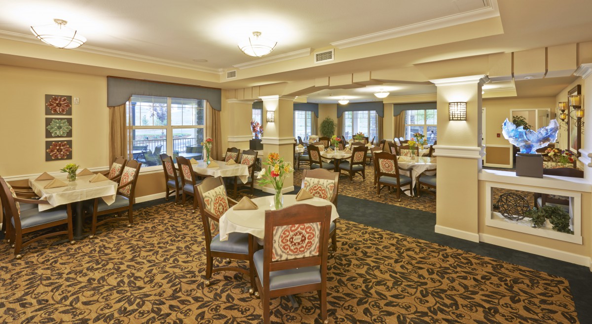 A spacious dining room with elegantly arranged tables and chairs, featuring a warm and inviting decor.
