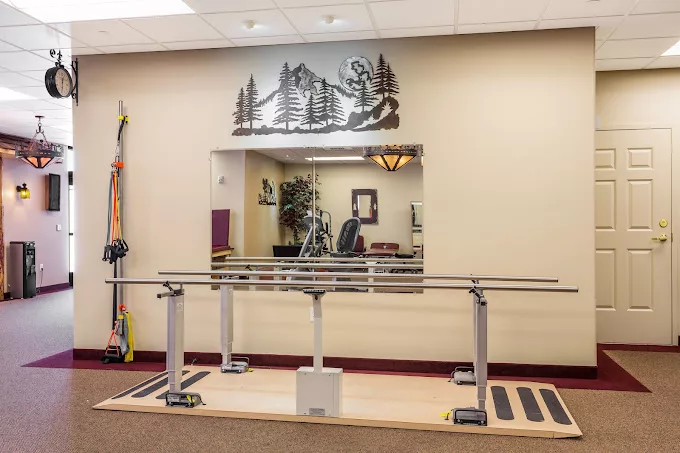 An interior view of a physical therapy room with handrails and a mirror for rehabilitation exercises.