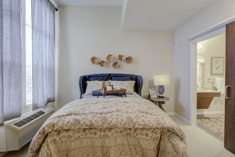 A cozy bedroom with a plush bed, decorative wall art, and a bedside lamp.