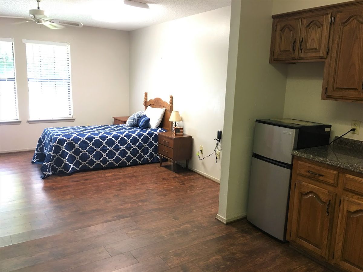A cozy studio apartment with a bed and a small kitchenette.