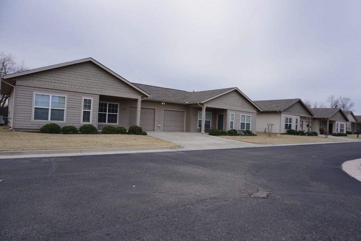 A single-story residential house with a driveway in a suburban area.