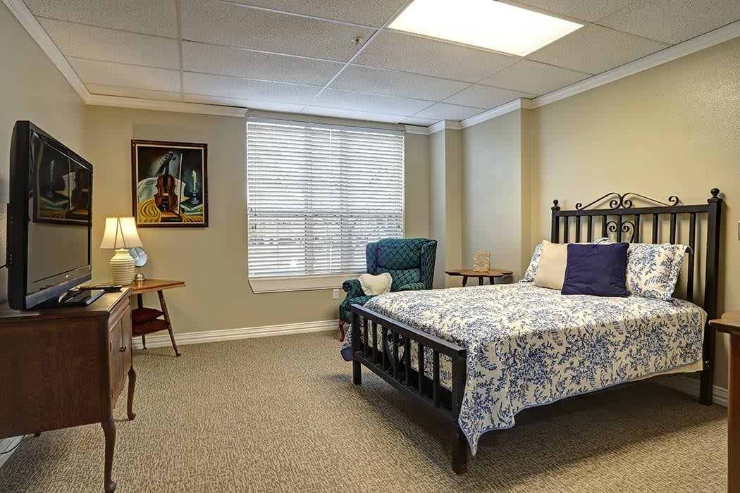 A cozy bedroom with a bed, chair, and decorative elements.