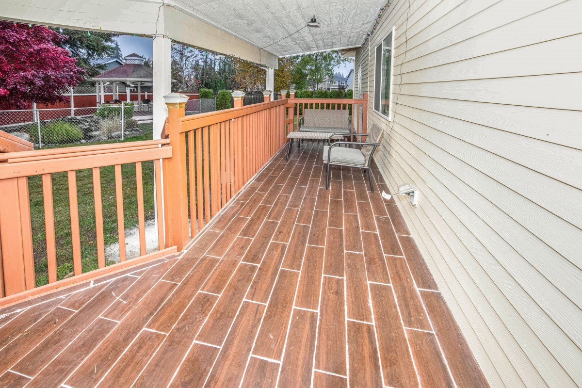 A spacious covered porch with wooden flooring and outdoor seating.