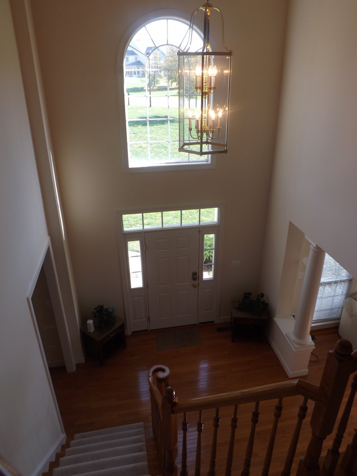 A spacious foyer with a chandelier, large window, and hardwood floors.