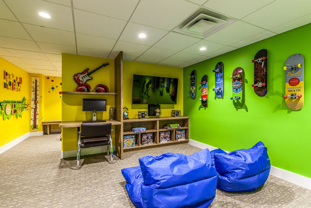 A vibrant gaming room with bean bags, skateboards on the wall, and a central TV setup.
