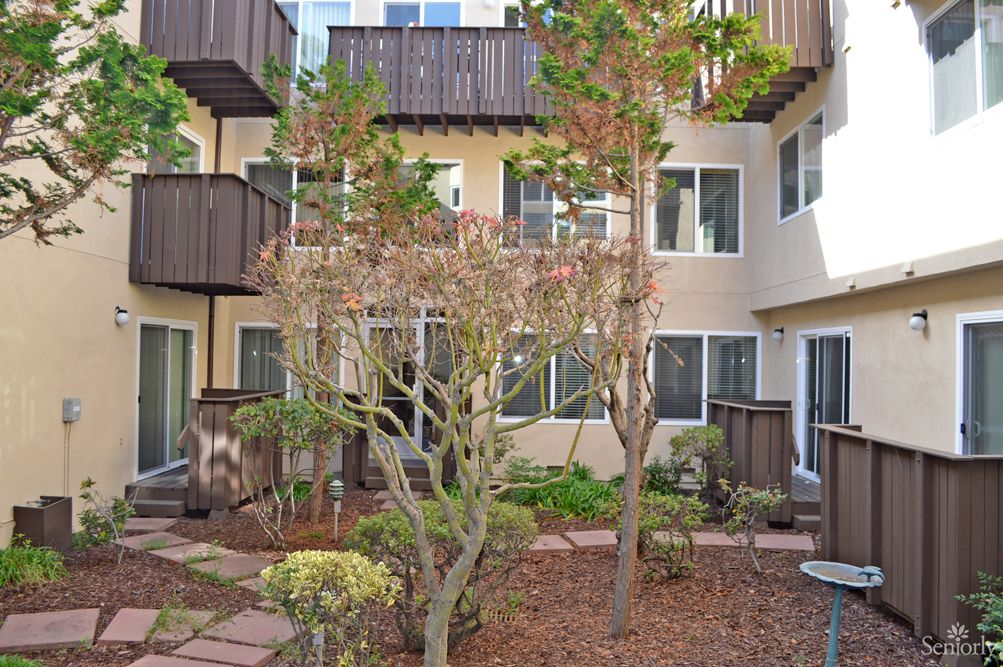 A landscaped courtyard surrounded by an apartment building with balconies and windows.