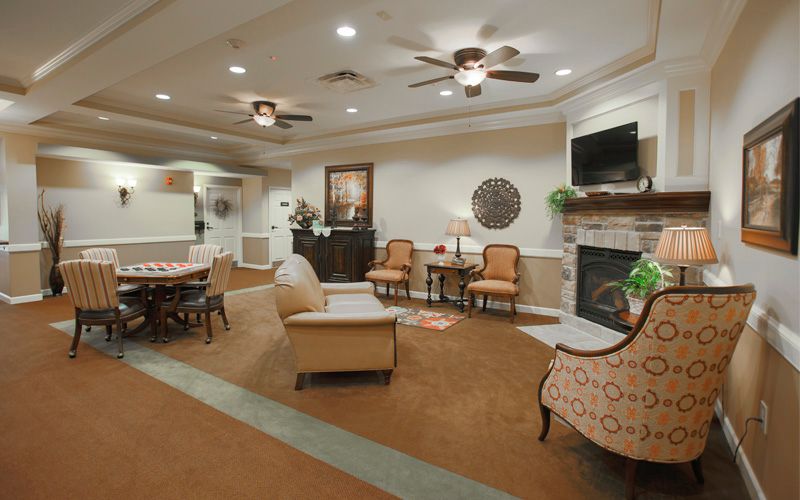 A cozy living room with elegant furnishings, featuring a fireplace, ceiling fans, and comfortable seating.