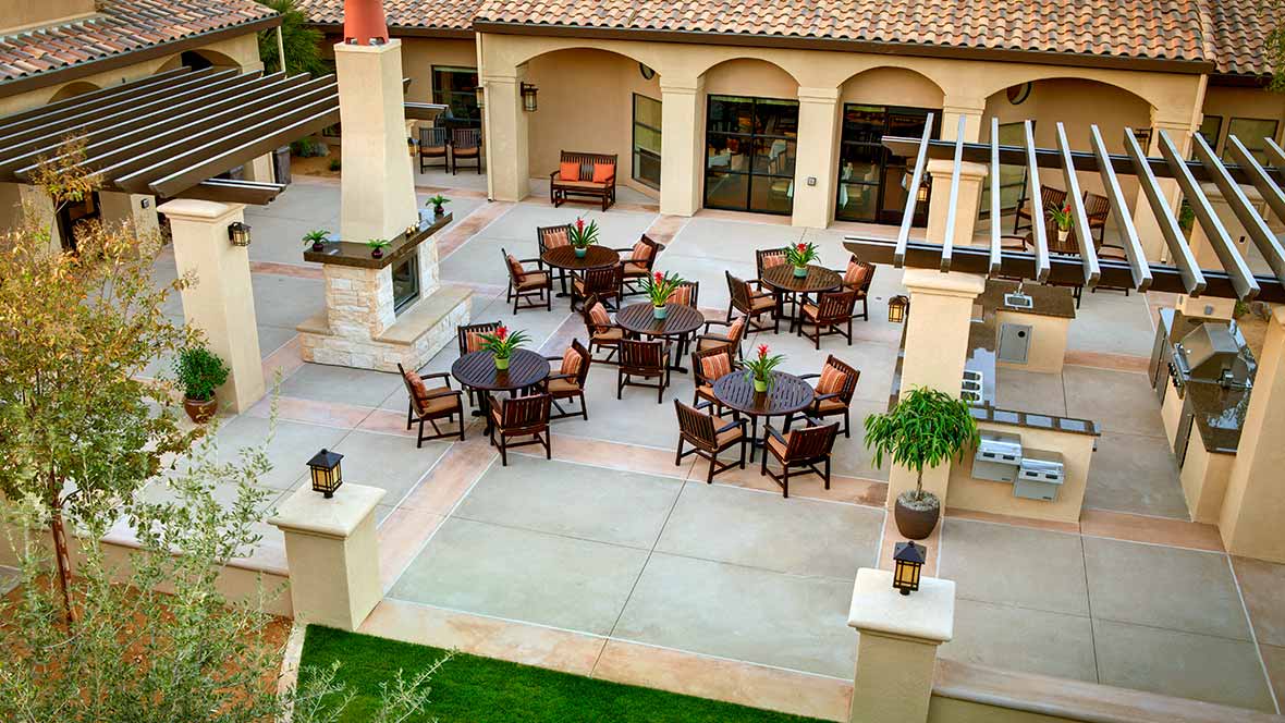 A well-arranged outdoor patio area featuring several tables and chairs in a spacious courtyard.
