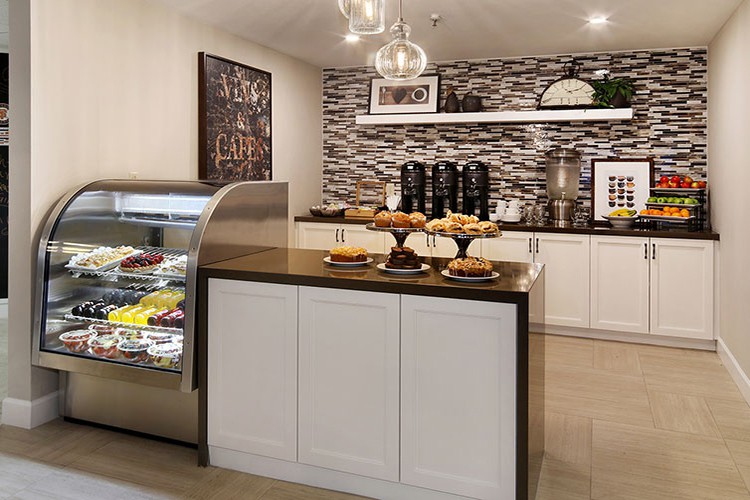 A modern cafe interior with a dessert display and coffee station.