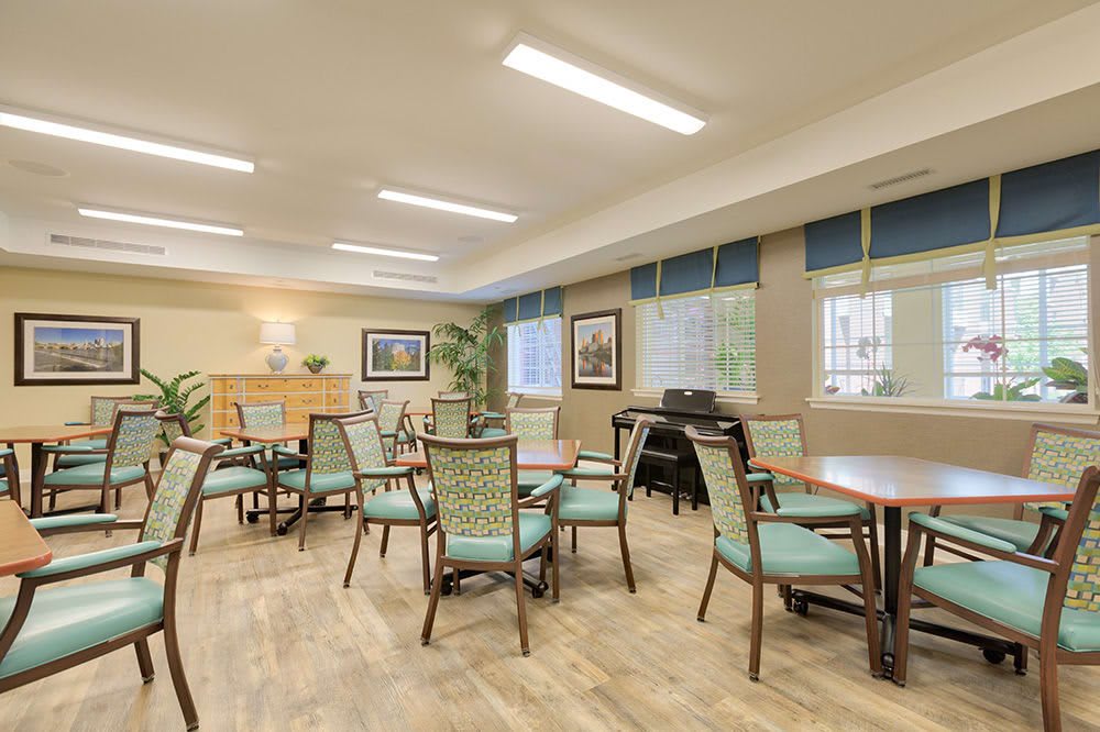 A well-lit room with multiple chairs and tables, featuring large windows and tasteful decor.