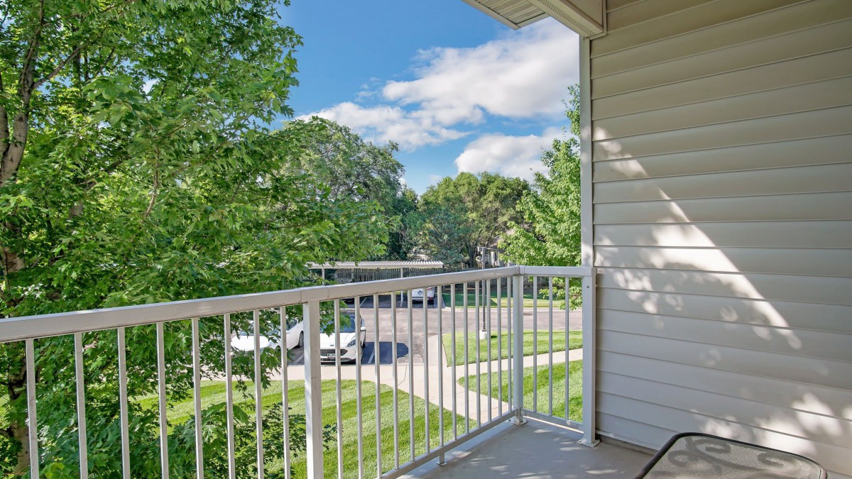 A view from a balcony overlooking a suburban neighborhood with trees and clear skies.