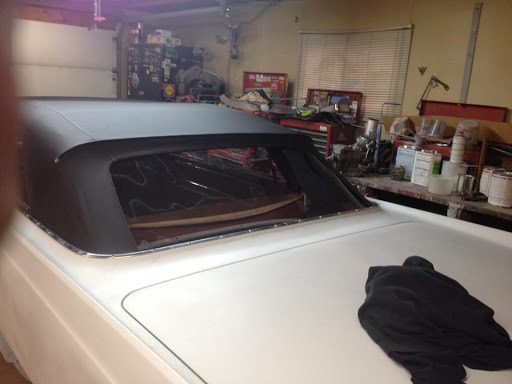 A close-up view of a classic convertible car's rear section in a garage.
