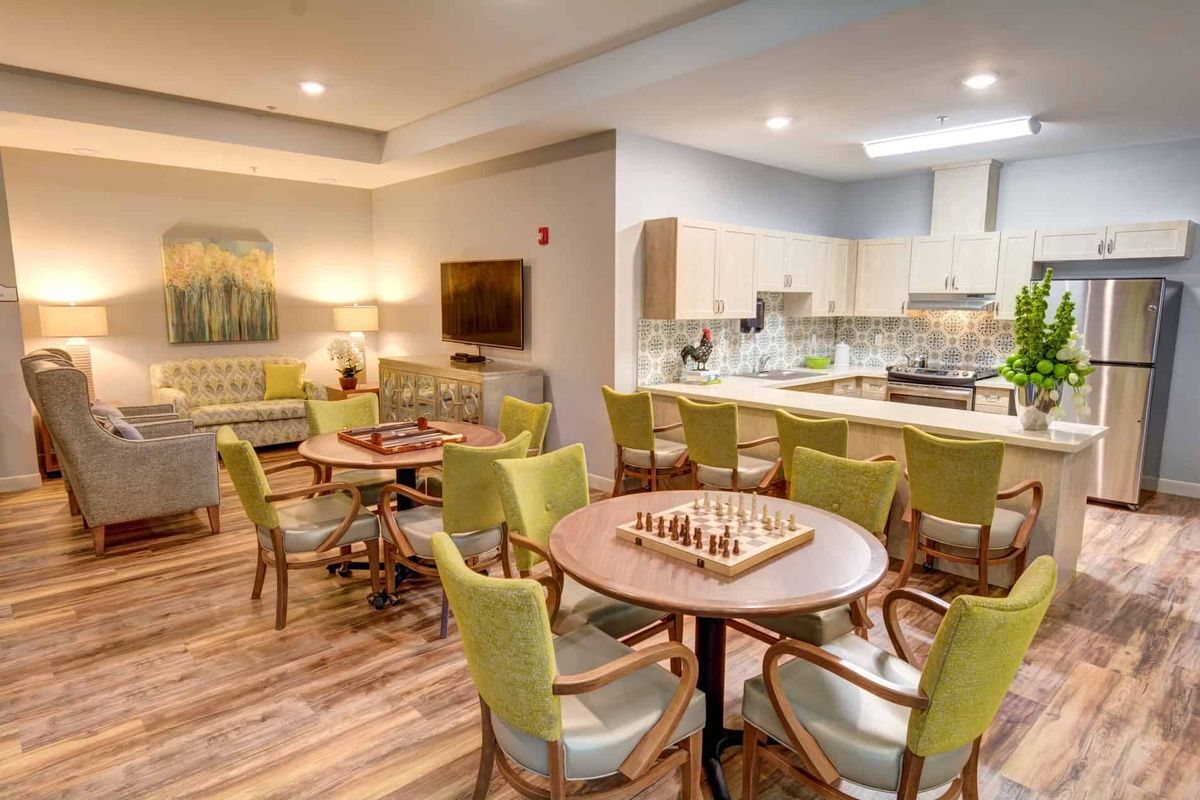 A modern communal space featuring a kitchen, living area, and tables with chess boards.