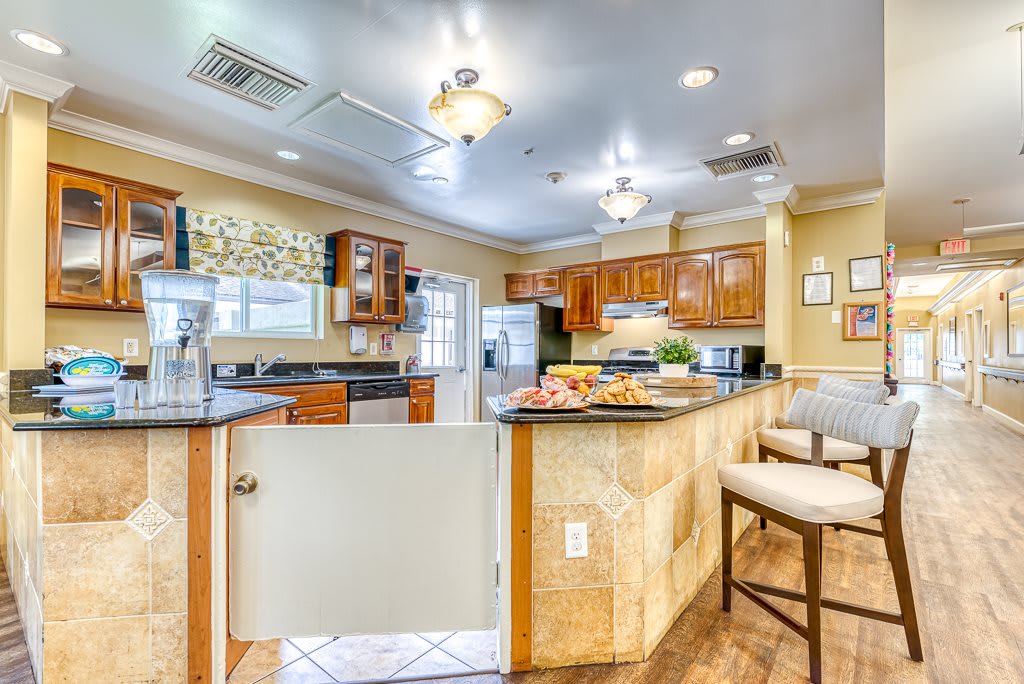 A modern kitchen with wood cabinets, bar stools, and bright lighting.