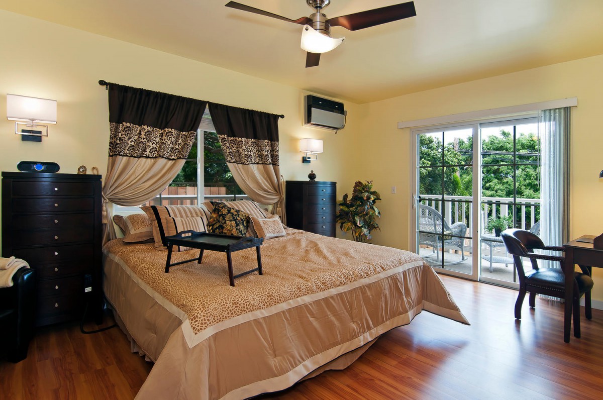 A cozy bedroom with a large bed, ceiling fan, and sliding doors leading to a balcony.