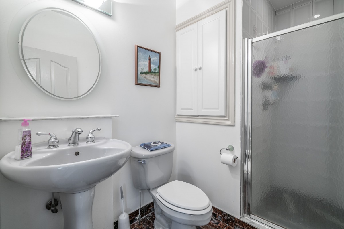 A compact and modern bathroom with a sink, toilet, and glass-enclosed shower.