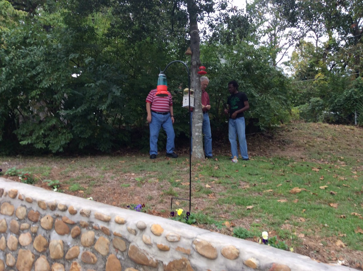 Scarecrows set up in a garden area with trees in the background.