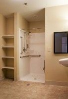 Accessible bathroom with shower, grab bars, and shelving.