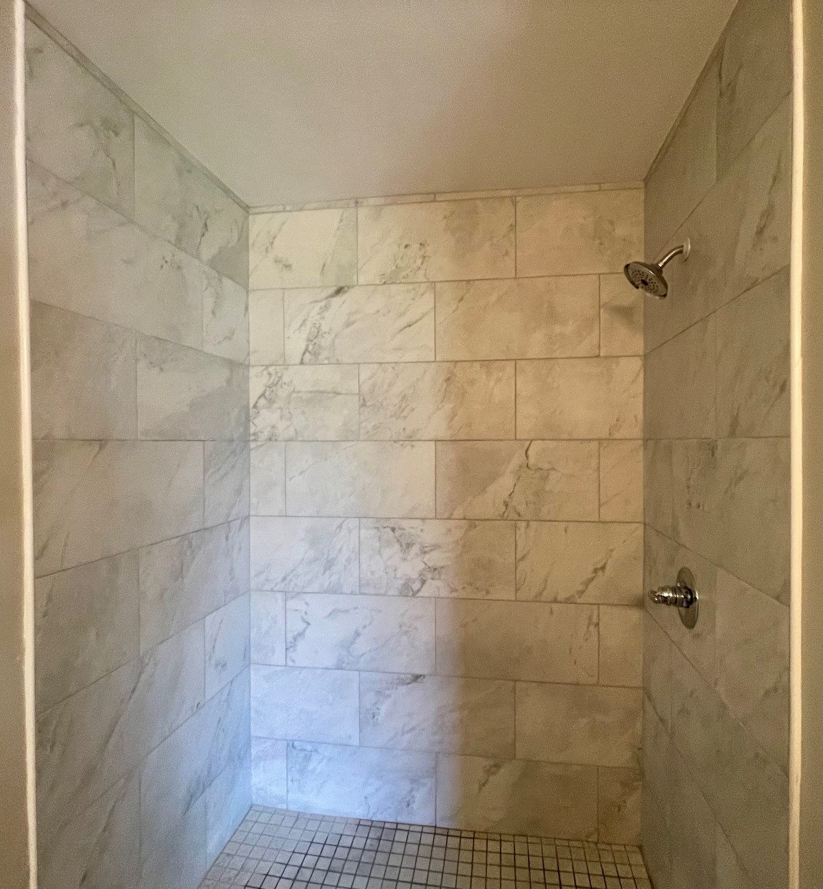 A minimalist shower with marble-like tiles.