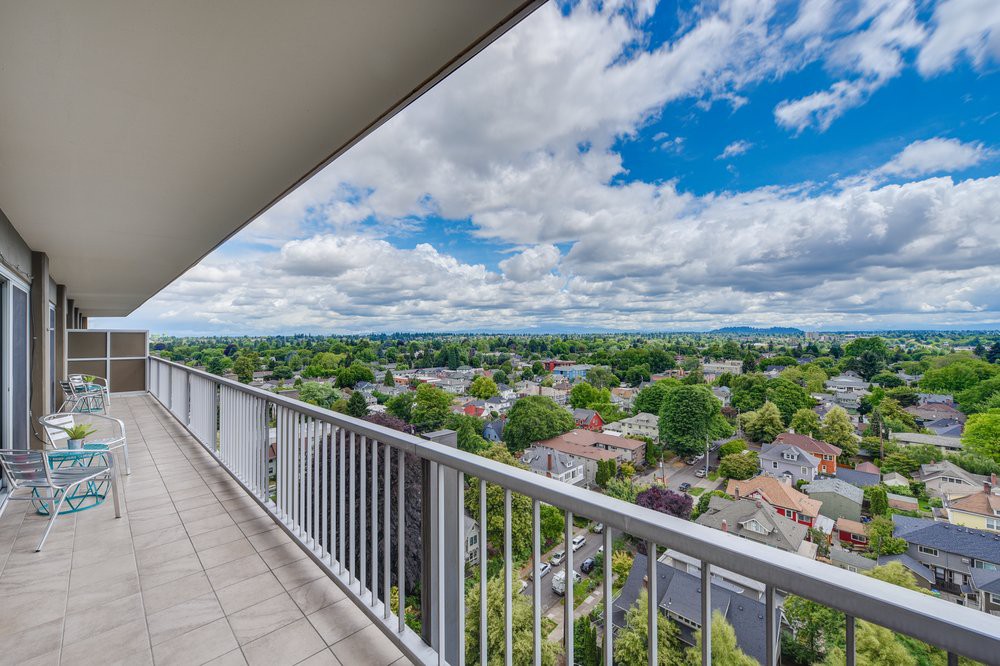 A scenic view from a balcony overlooking a sprawling cityscape under partly cloudy skies.