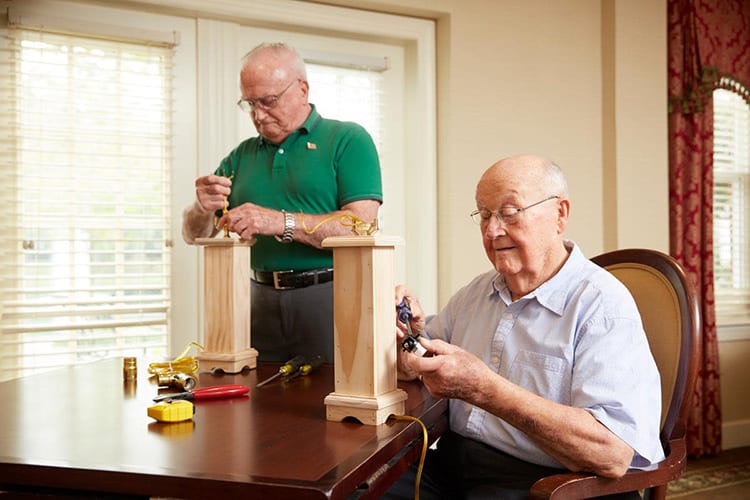 Two seniors engaged in a woodworking project indoors.