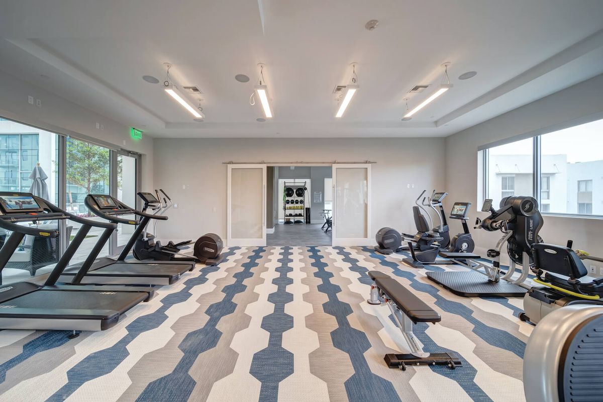 A modern gym with various exercise equipment including treadmills and weights.