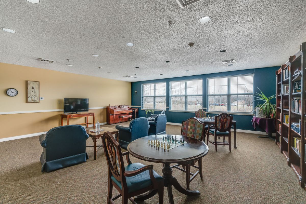 A cozy game room with tables and chairs, featuring a chessboard and a television.